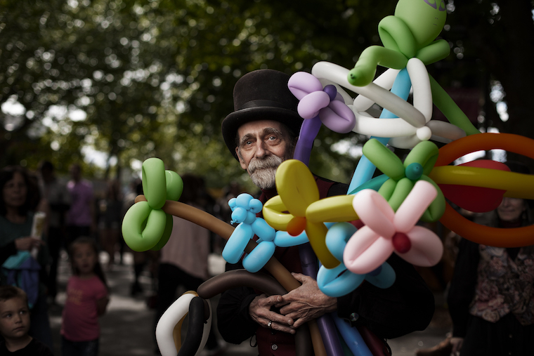 Michael and his wife Miriam are masters at twisting balloons, and they’re great with a crowd. Michael was about ready to pack up and head home for the day, but was kind enough to take a few minutes to let me photograph him, while his line of impatient customers began to pile up.